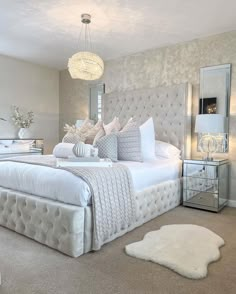 a large white bed sitting in a bedroom next to a window with a chandelier