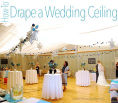 a couple getting married in front of a large tent with white tablecloths and blue decorations