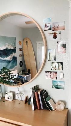 a mirror that is on the wall above a table with books and other items in front of it