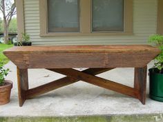 a wooden bench sitting in front of a house next to two potted planters