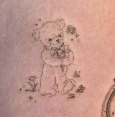 a small teddy bear tattoo on the stomach