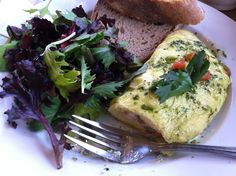 an omelet and salad on a plate with a fork