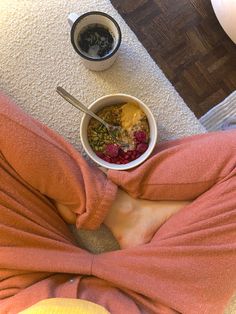 a person sitting on the floor in front of a bowl of cereal and yogurt