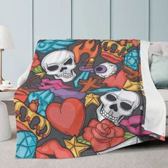 a blanket with skulls and roses on it in front of a white couch next to a lamp