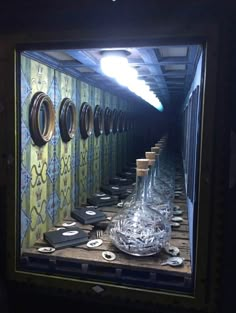 a long row of bottles sitting on top of a wooden table in front of a mirror