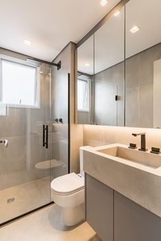 a bathroom with a toilet, sink and shower stall in the middle of it's floor to ceiling glass walls