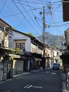 an empty street with cars parked on both sides and telephone wires above the buildings in the background