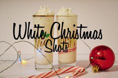 two glasses filled with whipped cream next to a candy cane and christmas ornament