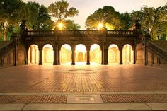 an open courtyard with arches and pillars lit up by the sun shining through the trees