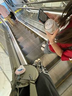 a woman standing on an escalator holding a cell phone