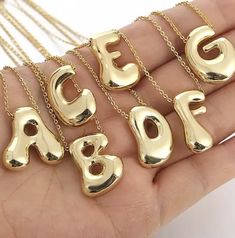 gold plated alphabet necklaces on a person's hand