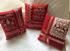 three red and white decorative pillows on a bed