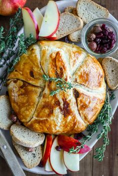 a white plate topped with an apple pie next to bread and cranberry sauce