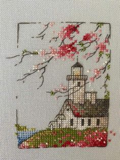 a cross stitch picture with flowers and a lighthouse