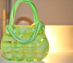 a green handbag sitting on top of a white table next to a light fixture