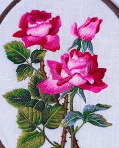 a close up of a embroidery on a piece of cloth with two roses in it