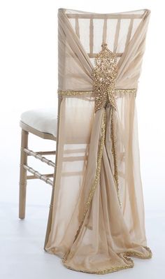 a chair with a sheer fabric and gold sequins on the back, sitting in front of a white backdrop