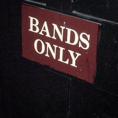 a red sign that says bands only on the side of a black building with white lettering