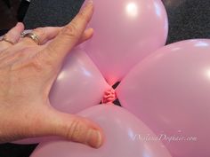 a person's hand reaching for some pink balloons