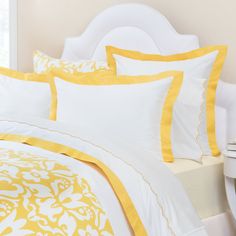 a white bed with yellow and white comforters