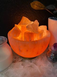 an orange bowl filled with rocks next to candles