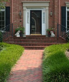 a red brick house with black shutters and white front door on the steps leading up to it