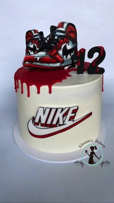 a white cake with red and black nike shoes on it's bottom layer, covered in icing