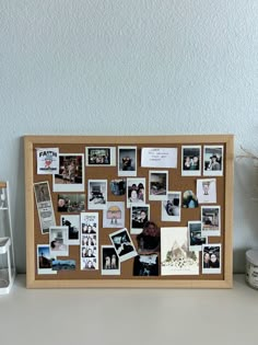 a cork board with pictures and magnets on it next to a vase filled with flowers