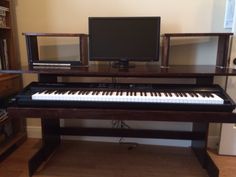 a computer desk with a keyboard, monitor and speakers on it in front of a bookshelf