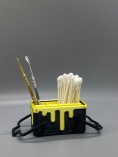 toothbrushes in holder with yellow drips and black cord on gray background,