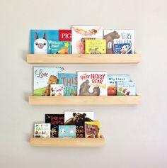 two wooden bookshelves with children's books on them against a white wall