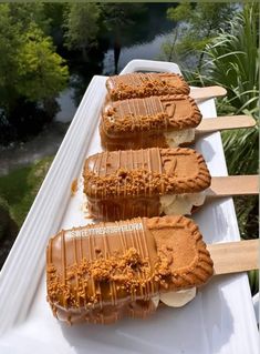 three ice cream sandwiches with caramel toppings are on a long white tray, ready to be eaten