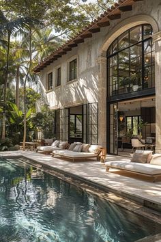 an outdoor swimming pool next to a large house with glass doors and windows on the side