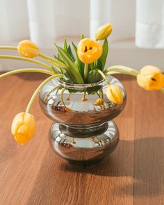 some yellow flowers are in a clear vase