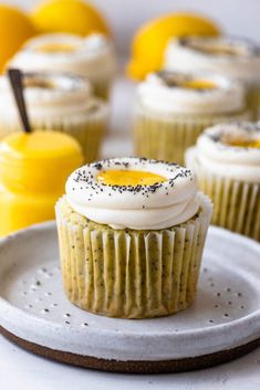 cupcakes with white frosting and sprinkles on a plate next to lemons