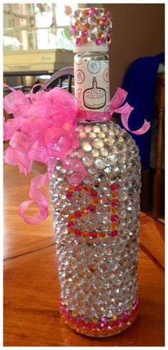 a bottle filled with lots of pink and silver beads on top of a wooden table