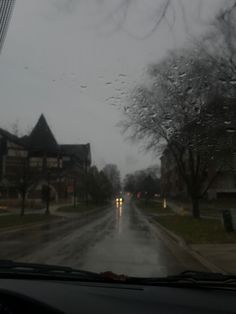 rain is falling down on the street in front of houses