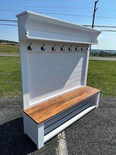 a white bench sitting in the middle of a parking lot next to a green field