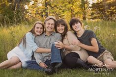 three people sitting on the ground with their arms around each other and smiling at the camera