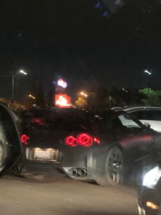 two cars are parked on the side of the road at night with traffic lights in the background