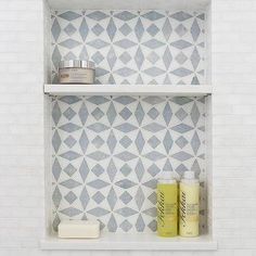 two shelves with different items on them in a white tiled wall behind the toiletries