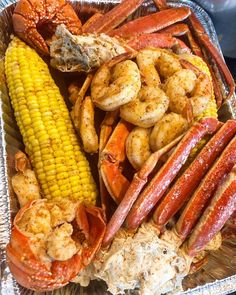 lobsters, corn on the cob and shrimp in a tin container with seasoning