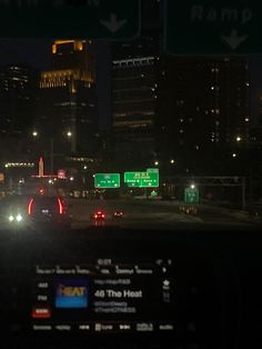 cars driving down the highway at night with city lights in the background