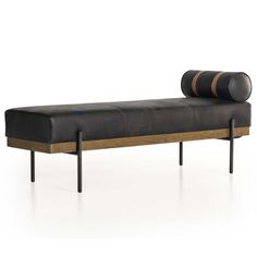 a black leather bench with wooden legs and a round seat cushion on the back, in front of a white background