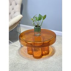 a glass table with a potted plant sitting on it's top in front of a chair