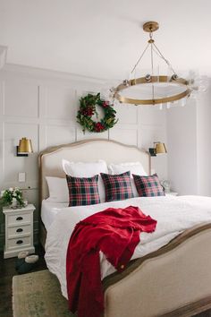 an instagramted photo of a bed with red and white blankets, plaid pillows, and wreaths on the headboard