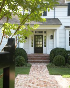 a white house with a brick walkway leading to the front door