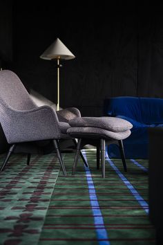 two chairs sitting next to each other on top of a carpeted floor in front of a lamp