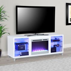 a white entertainment center with an electric fireplace in front of a flat screen tv mounted on a wall