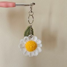 a crocheted keychain with a flower on the front and bottom, attached to a hook